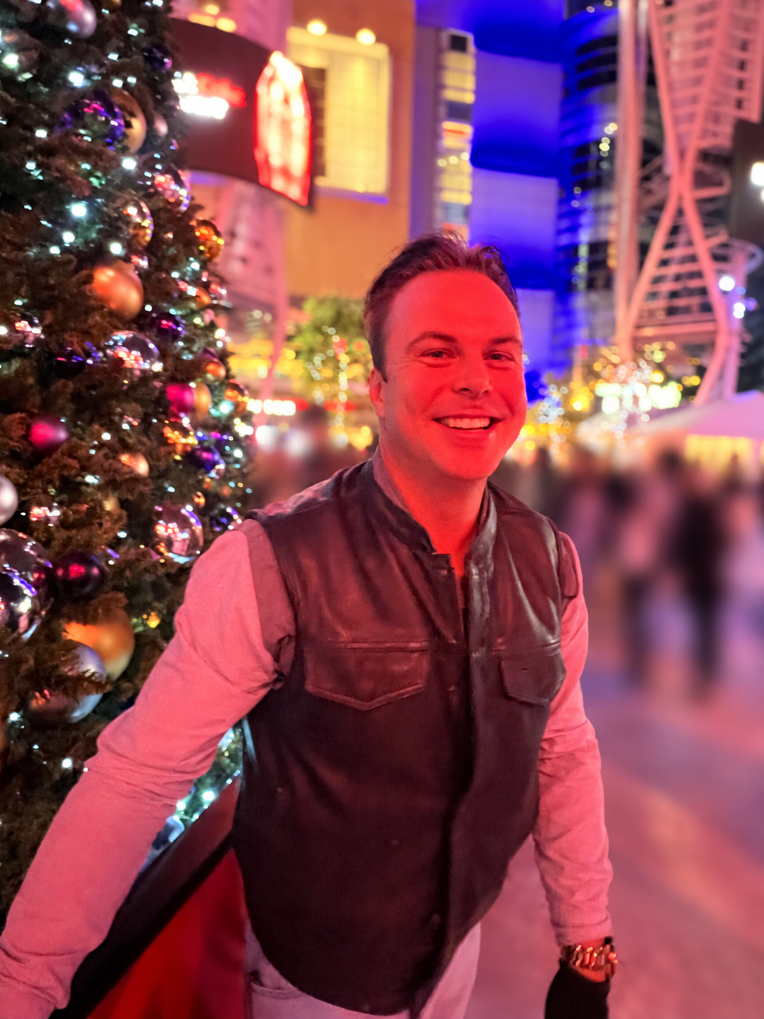 Austin Mitchell beside an outdoor festive Christmas tree